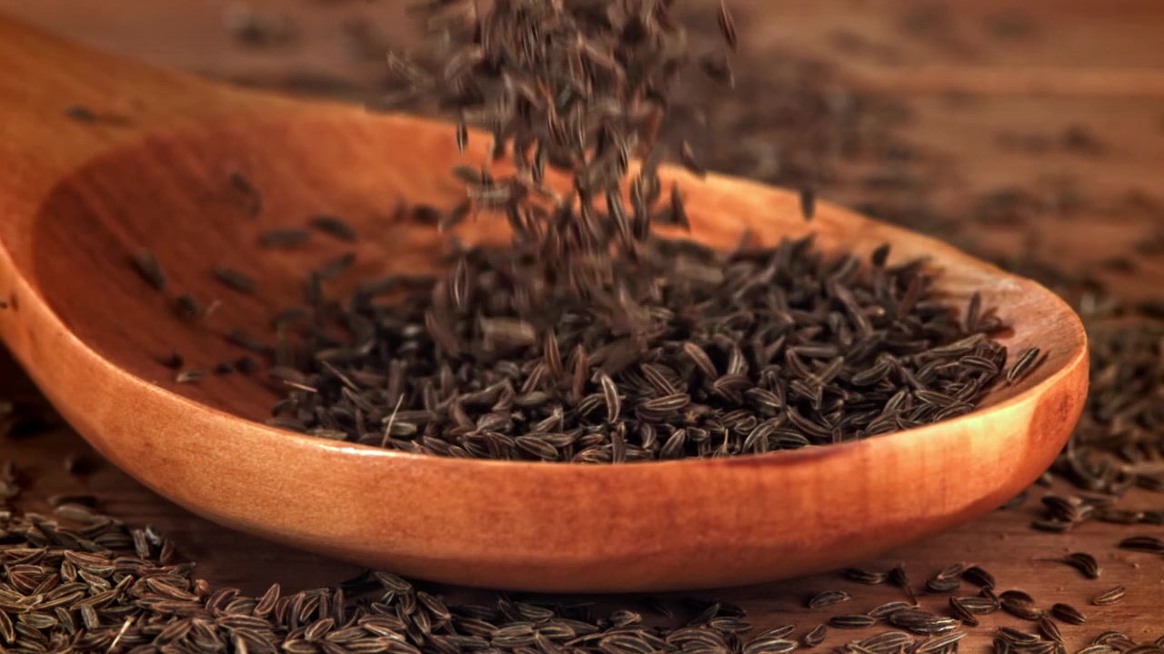 Cumin Seeds Falling into a Wooden Spoon in Slow Motion
