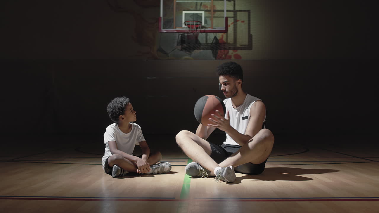 Basketball Player Talking to Boy on Dark Court