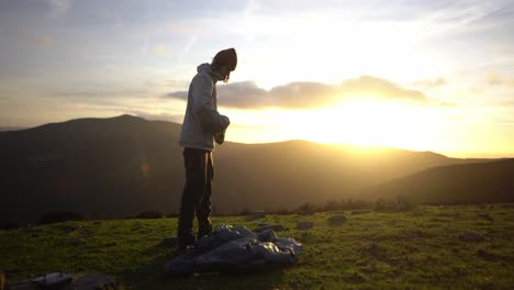 Caucasian-white-young-man-is-preparing-to-pitch-a-tent-after-hiking