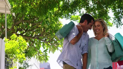 una pareja sonriente caminando con una bolsa de compras en un día soleado