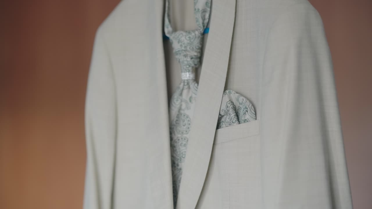 Beige wedding suit with matching patterned tie and pocket square displayed neatly
