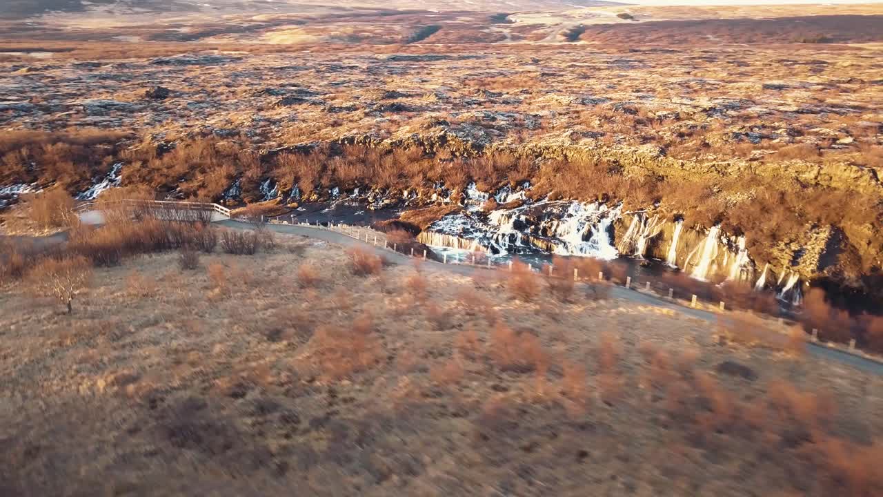 drone con movimientos cinematográficos muestra una hermosa cascada islandesa, hraunfossar, a la luz del atardecer desde múltiples ángulos