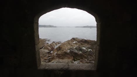 mirando a través de la apertura de la ventana en el castillo fuerte, falmouth con st mawes en el fondo