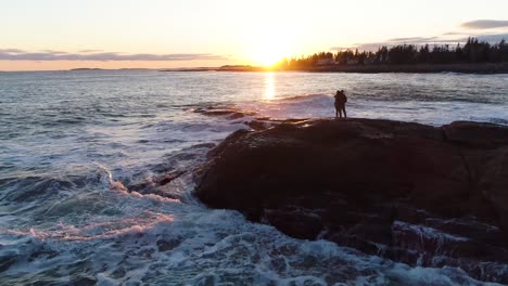 couple kissing by the shore while watching the sunset