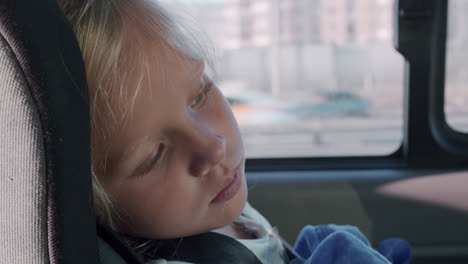 tired little girl in car safety seat
