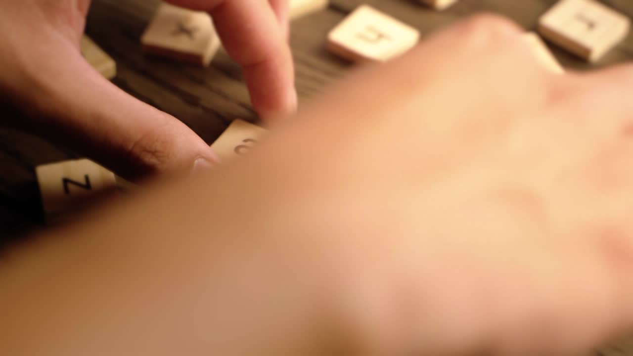 A hand arranges wooden tiles to spell the word art on a rustic wooden surface with warm lighting.