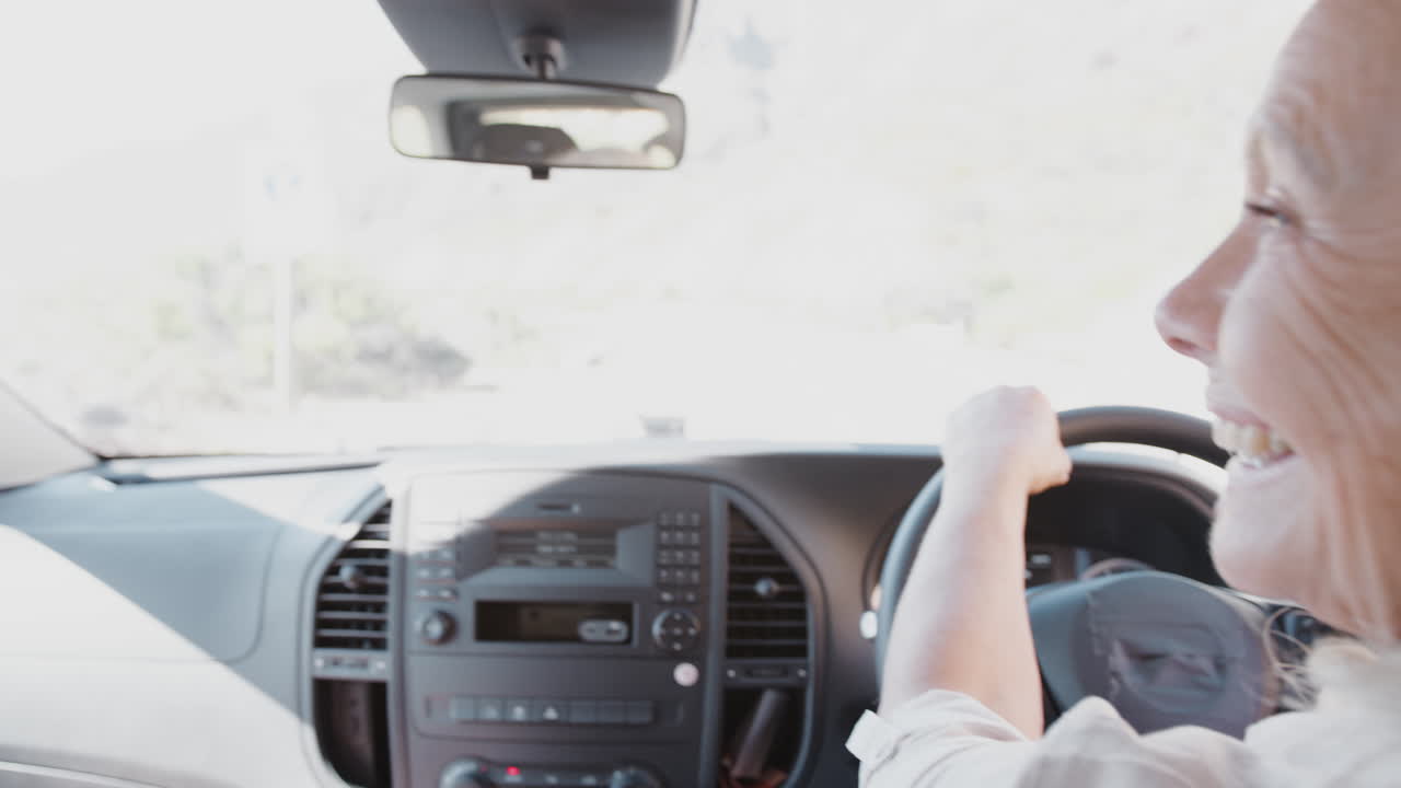 시골 도로를 따라 렌터카를 운전하는 휴가 중인 노인 부부의 내부 모습