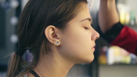 makeup artist applies concealer on the face of a young girl. base for perfect makeup. slow motion shot