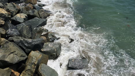 Waves rushing up onto rocks at Redondo Beach Pier in Southern California