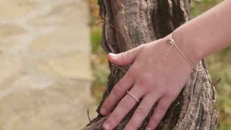 Hand-with-jewellery-gently-caress-aged-vine-tree-wood-texture-close-up