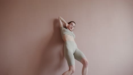 woman posing against a pink wall in an athletic outfit