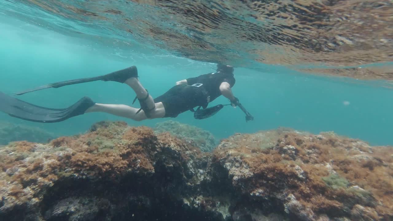 Spearfisher looking for fish in shallow crystal clear waters in the mediterranean sea