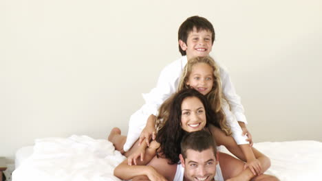 Familia-Acostada-En-La-Cama-Sonriendo-Divirtiéndose