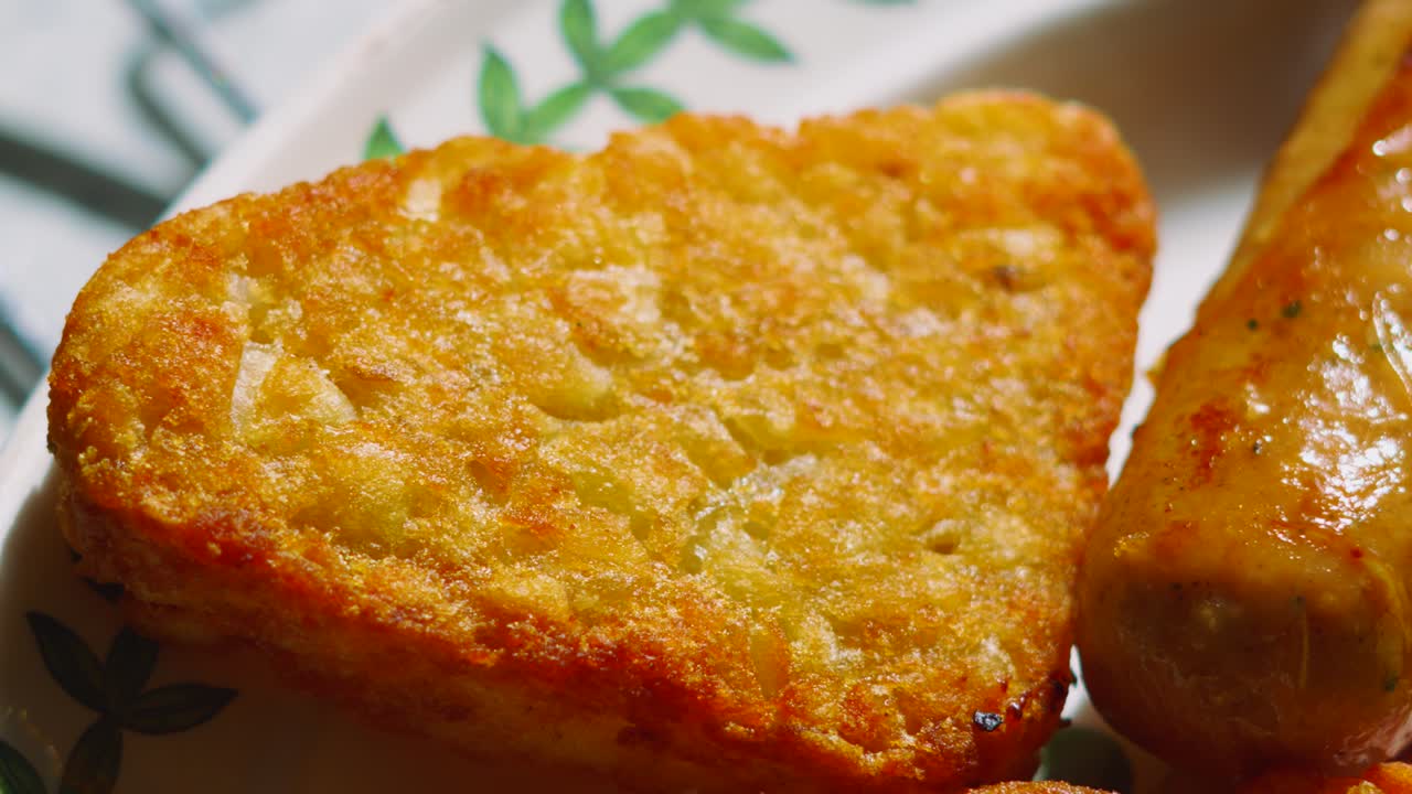 Close Up Details of Crispy Hash Brown and Sausage on Breakfast Plate in Morning Sunlight. Potato Based Side Dish.