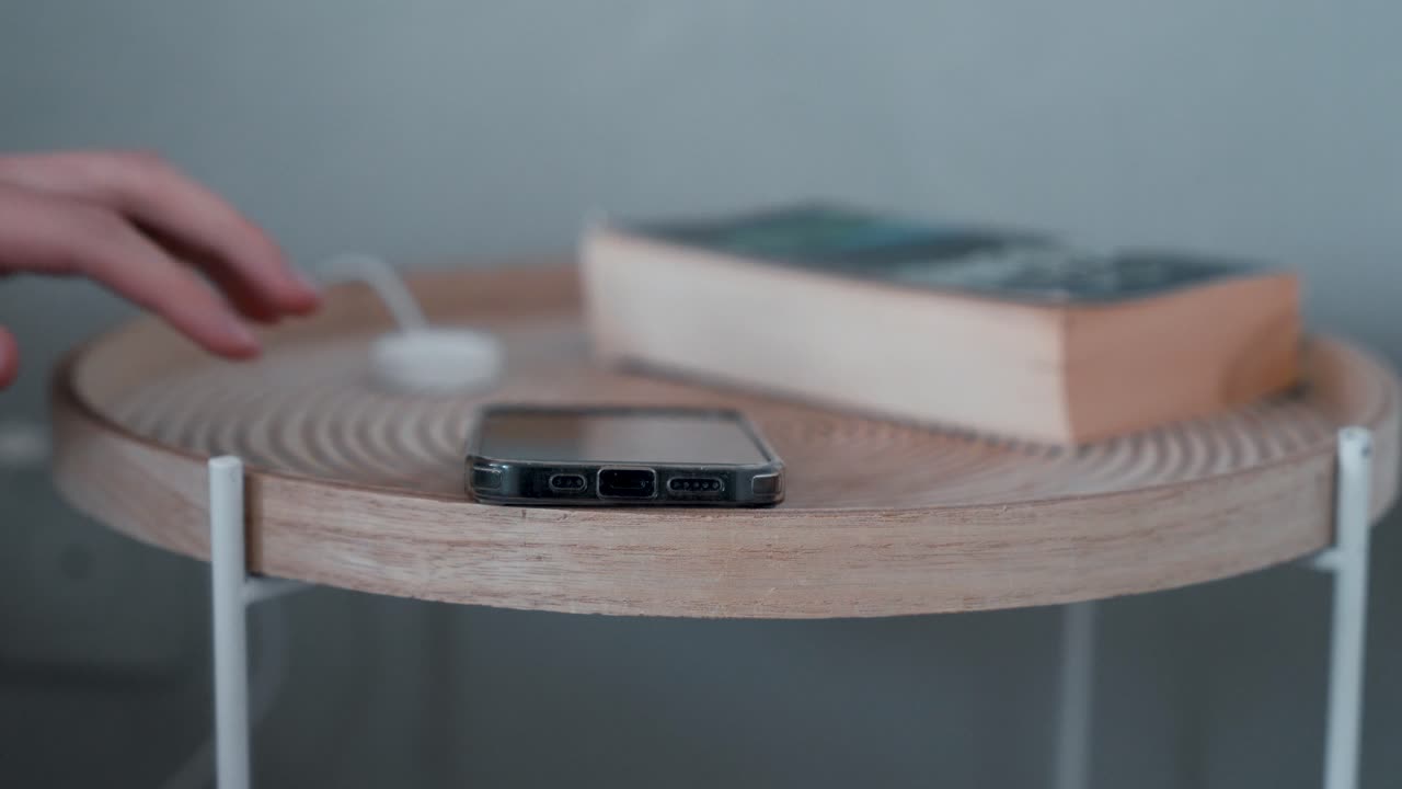 Man hand grabbing smartphone on table nightstand next to bed, reaching to mobile phone in morning evening living in social digital world.