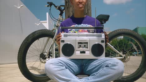 dolly shot backwards of young african american women with boom box on lap