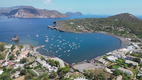 Vulcano-Island-Bay-with-Boats-and-Volcanic-Beach-at-Aeolian-Islands,-Italy---Aerial-4k