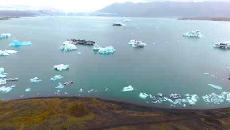 slow aerial revealing shot of icebergs melting at glaciers in iceland from climate change