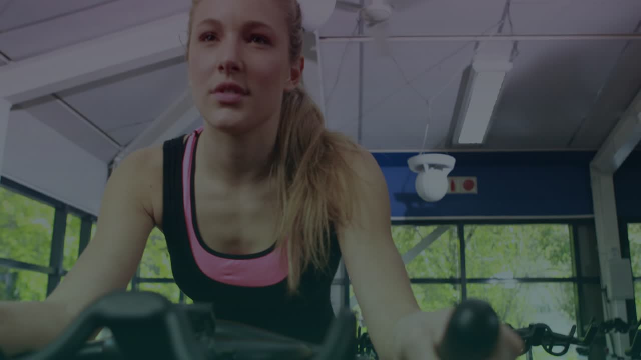 Donna che si china e pedala in bicicletta, iniziando l'allenamento con un auricolare, mentre un display HUD monitora la presa della barra per il fitness.