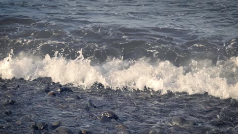 slow motion view of small waves breaking on rocky beach of tenerife