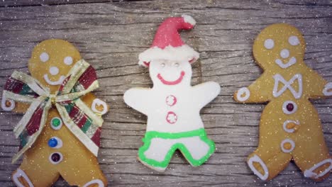 video composition with falling snow over desk with christmas ginger men