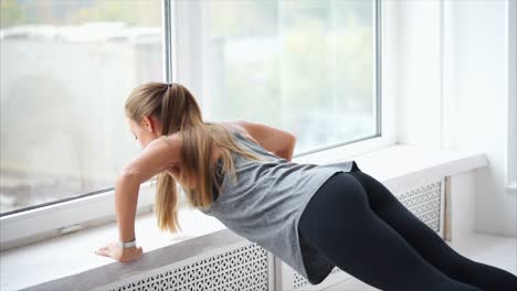 woman doing push-ups by a window
