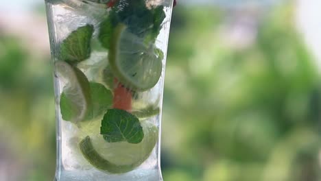 la paja de plástico naranja agita lentamente el cóctel de mojito congelado