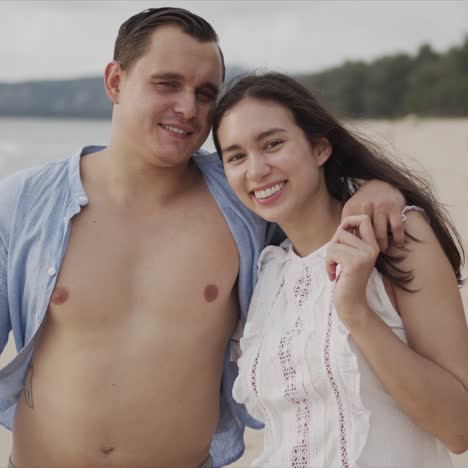 Happy-lovers-travelers-embracing-and-smiling-at-exotic-seaside