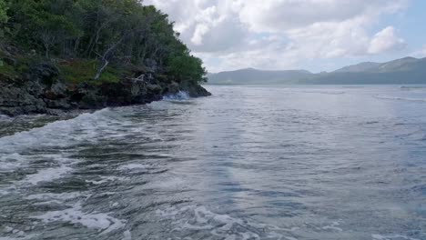 drone flying at low altitude over sea waters of la playita beach, las galeras in samana peninsula, dominican republic