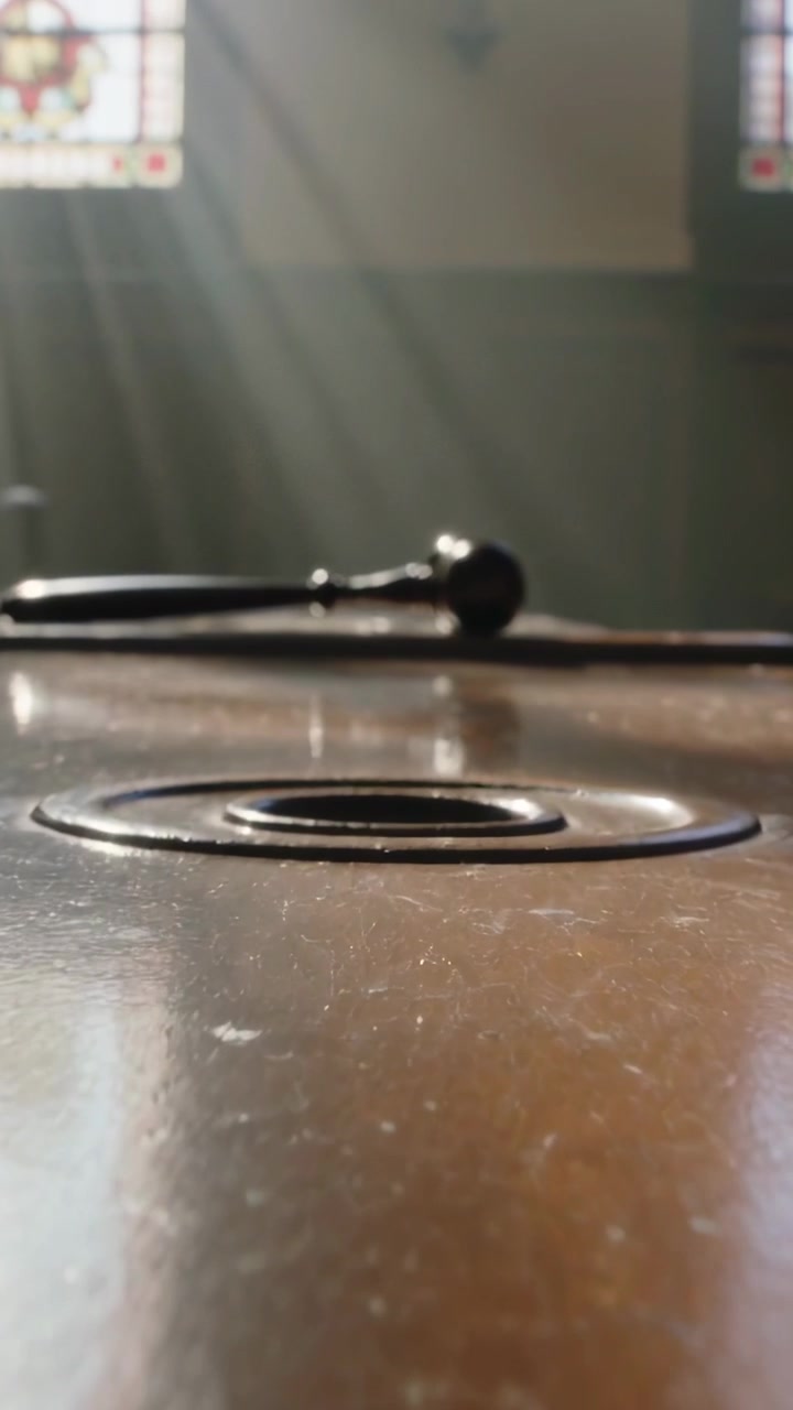 Vertical video: Pulling focus camera revealing ring on chapel table with mallet, light shafts