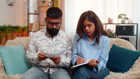 indian family couple man woman calculating bills money at home making notes reacting frustration