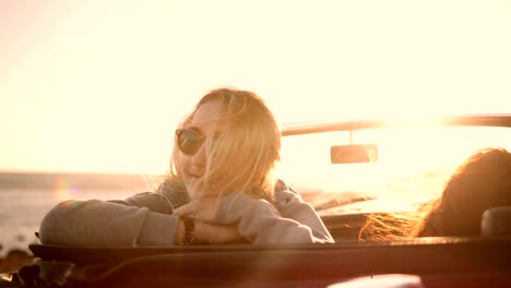 young women on road trip relaxing at beach at sunset