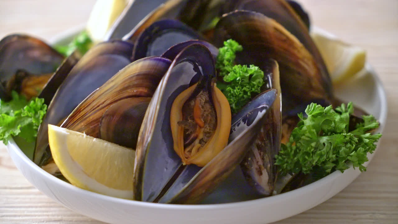 mejillones frescos con hierbas en un bol con limón
