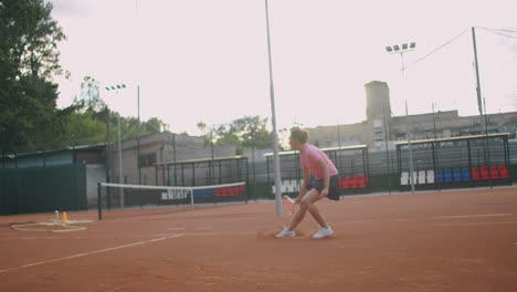 side view of a young caucasian woman playing tennis on a court returning a ball in slow motion