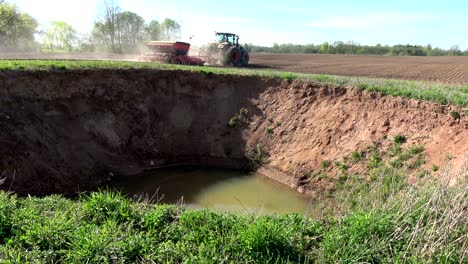 new karst sinkhole on farm field in lithuania and working tractor