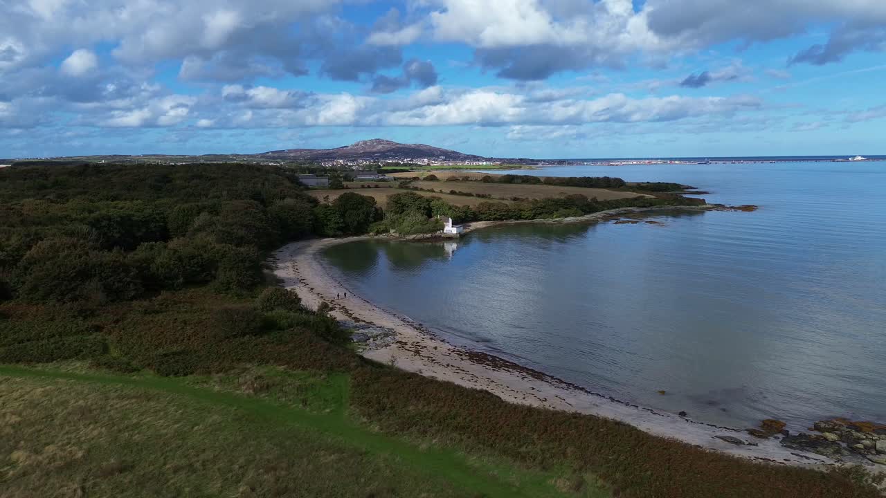 Aerial view across Welsh crescent bay under idyllic Holyhead mountain and distant farmland