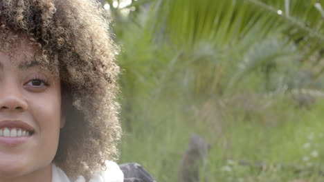 a young biracial woman with curly hair smiles gently, with copy space