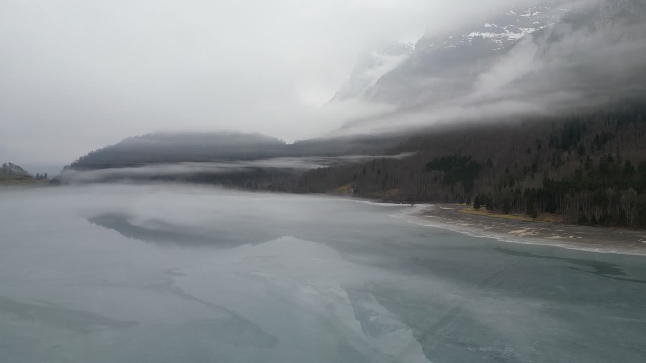 Klöntalersee Glarus Switzerland layers of mist over the lake that stills shows reflection of mountain