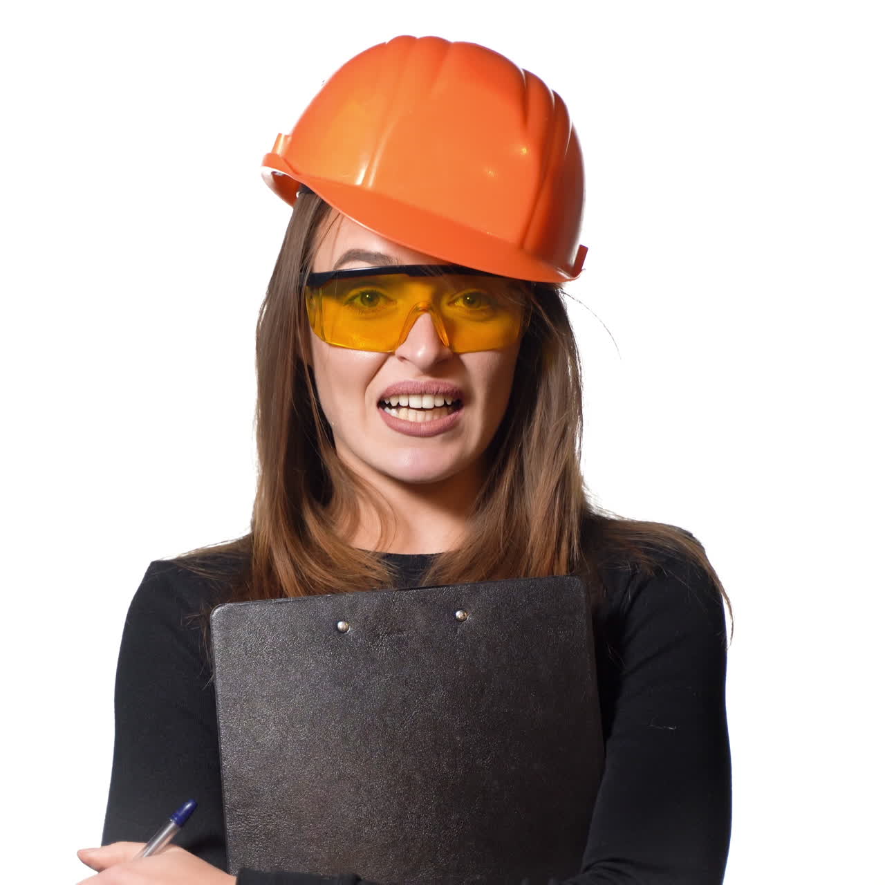 A beautiful woman in an orange helmet and in protective glasses holds a black planchette and pen in her hands and talks about something on a white background.