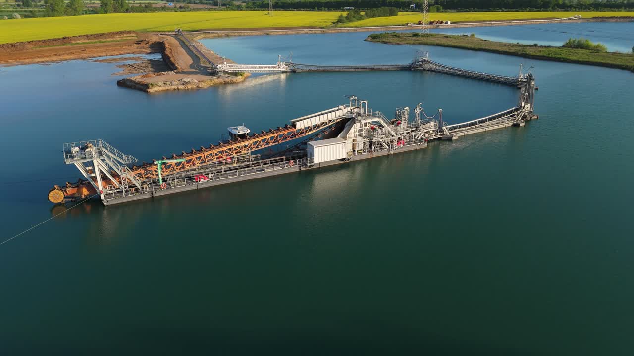 Aerial orbit of a floating dredger used for gravel extraction on a quarry lake near Leipzig. The calm water and industrial setup create a unique contrast with surrounding nature.