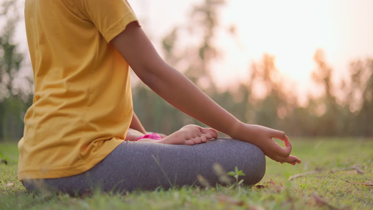 Tranquility woman performing pranamasana with earbuds in a park at sunrise, promoting wellness and mindfulness