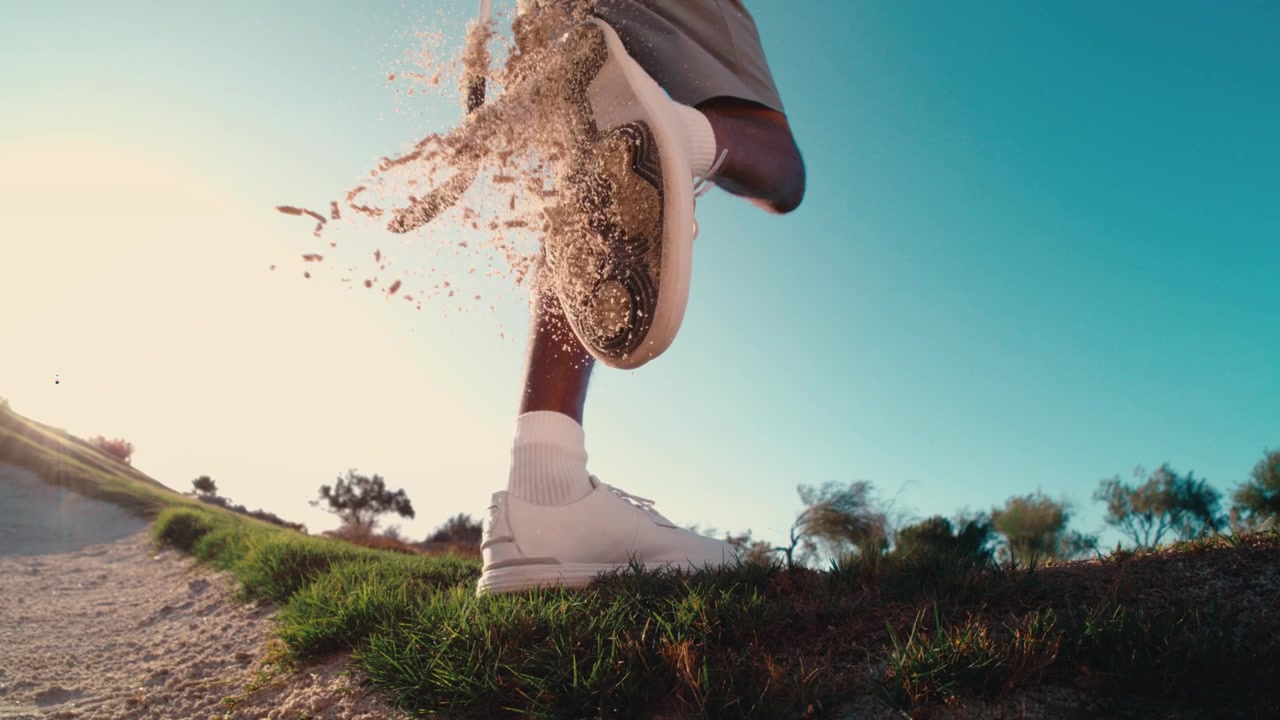 Golfer slår bunkersand af kilerne med en wedge, når han forlader bunkeren i ekstrem slow motion, sandrester regner overalt, solnedgang 4k 800fps vidvinkel push in