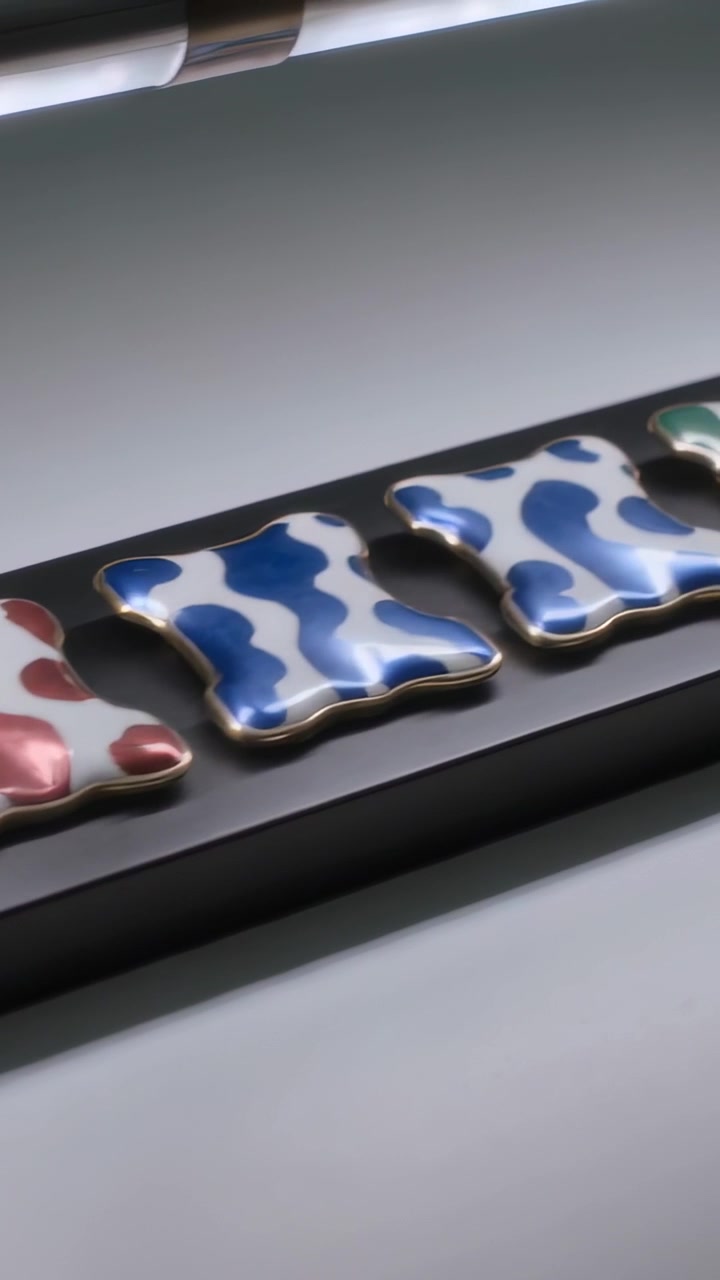 Vertical video: Panning camera revealing enamel tiles on black tray on sill, showing color patterns