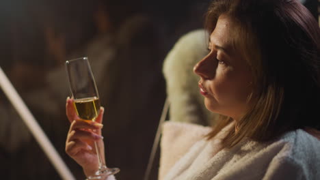 woman suffering from alcohol addiction drinks champagne from glass thinking about life. health problems and depression during hotel holiday slow motion