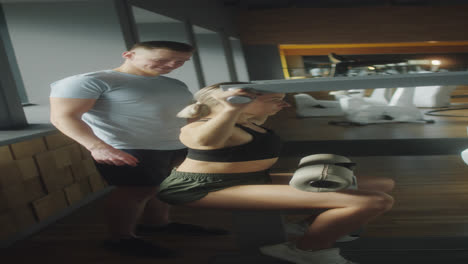 woman using gym machine with help of trainer