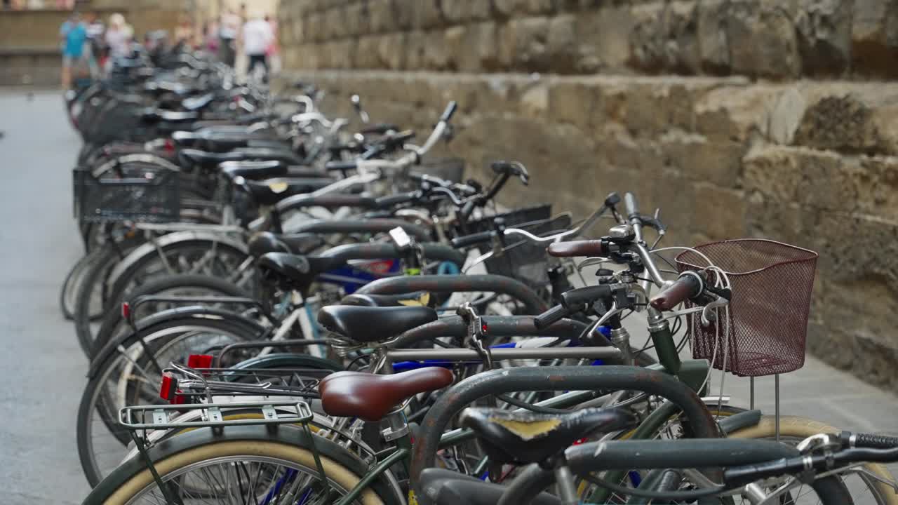 Fila di biciclette in parcheggio pubblico urbano in una città europea, legate a una stazione di aggancio. Molte bici bloccate insieme una per una in lunga fila a Firenze, Italia, nella zona della cittadella del centro storico. Stile di vita sostenibile.