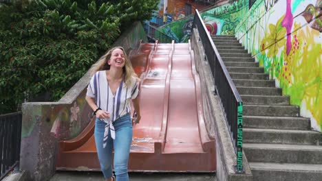 Pretty-Young-Woman-Goes-Down-Slide-in-Comuna-13-Neighborhood