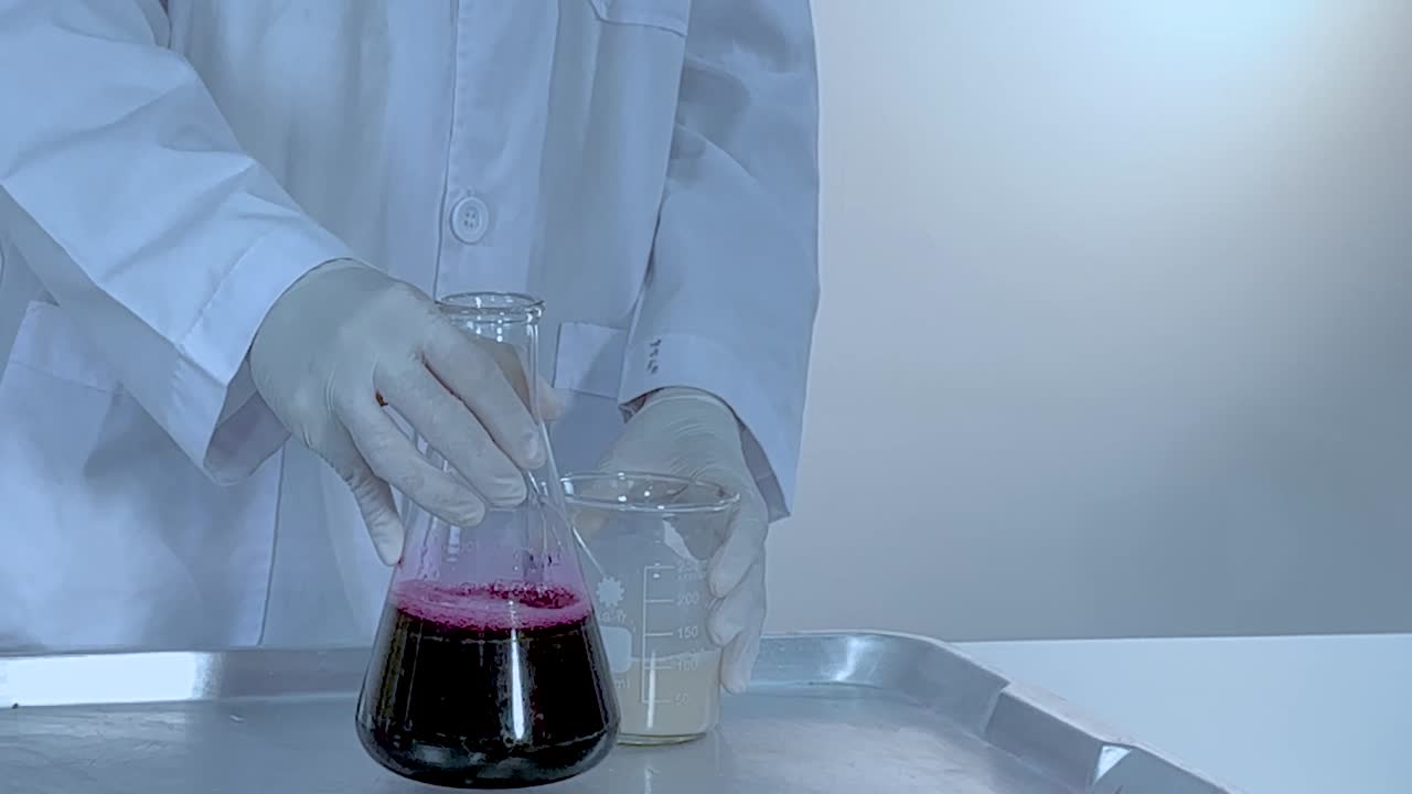 Observe the creation of pink foam as liquids react in a laboratory flask on a tray.