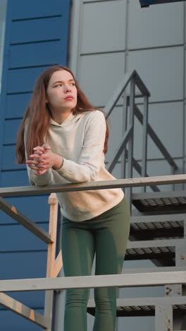 la mujer en las escaleras del edificio reflexiona sobre la depresión. la mujer joven contempla la actitud negativa hacia la vida rodeada de la serena calma de la puesta de sol.