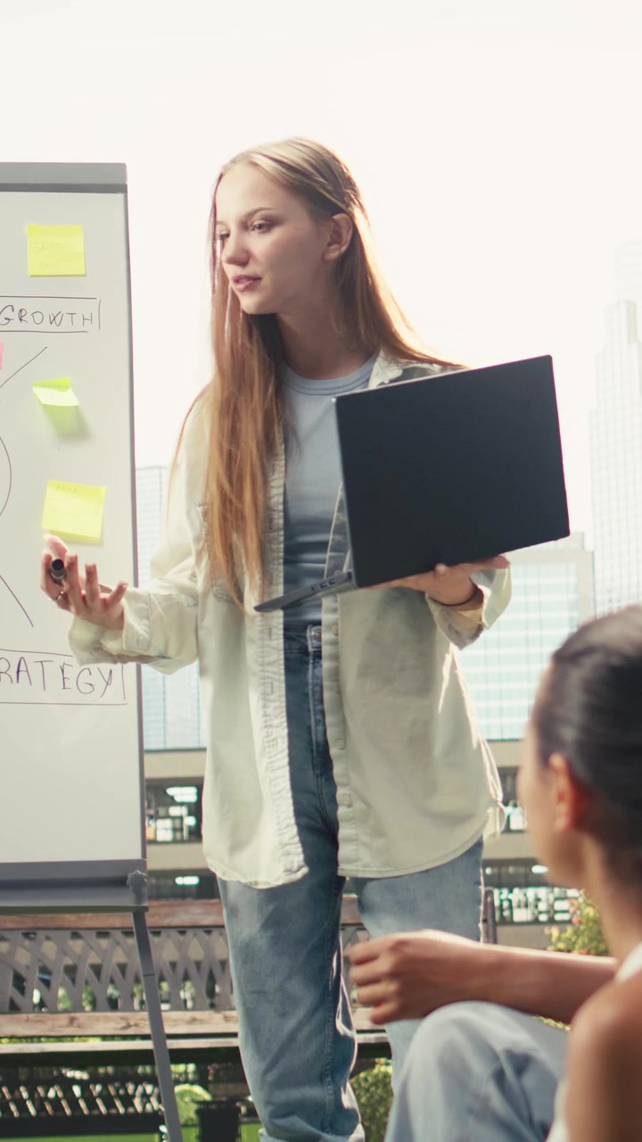 Vertical Video Student presenting ideas on whiteboard while holding laptop and marker